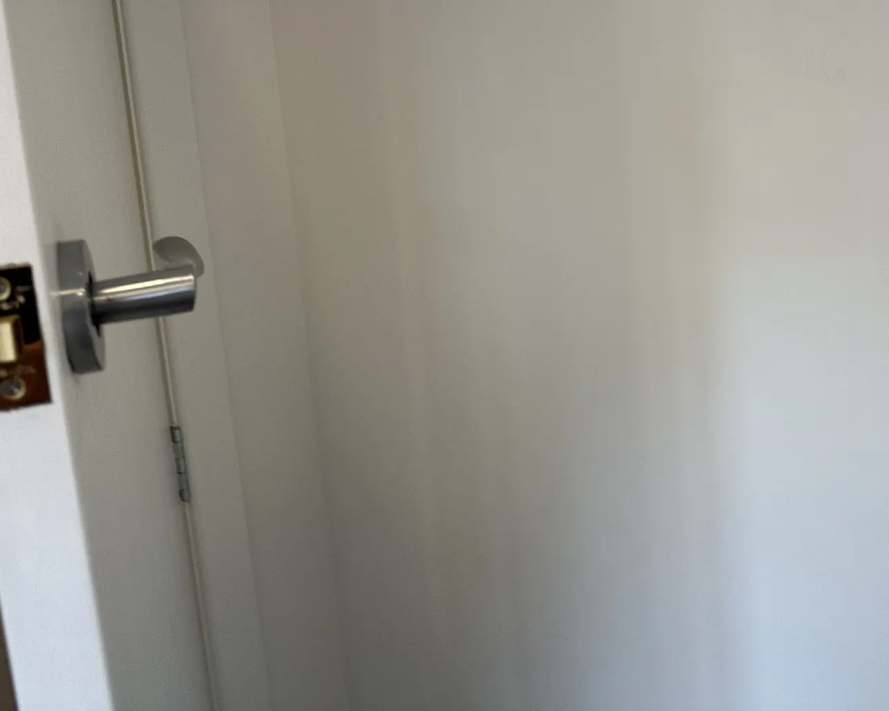 The same wall beside the door after the hole was filled, sanded and painted, with no trace of the repair
