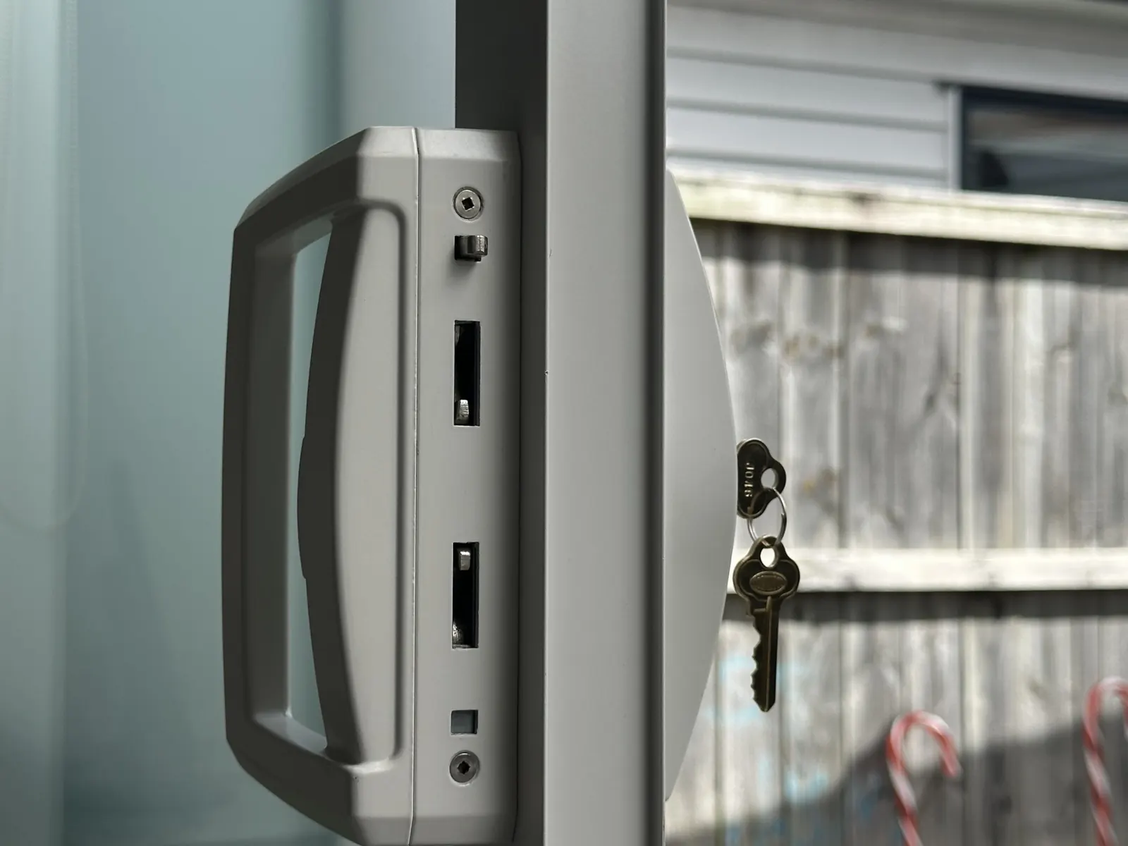 Repaired sliding door lock on an aluminium joinery door in Botany, with the two new keys hanging in the barrel