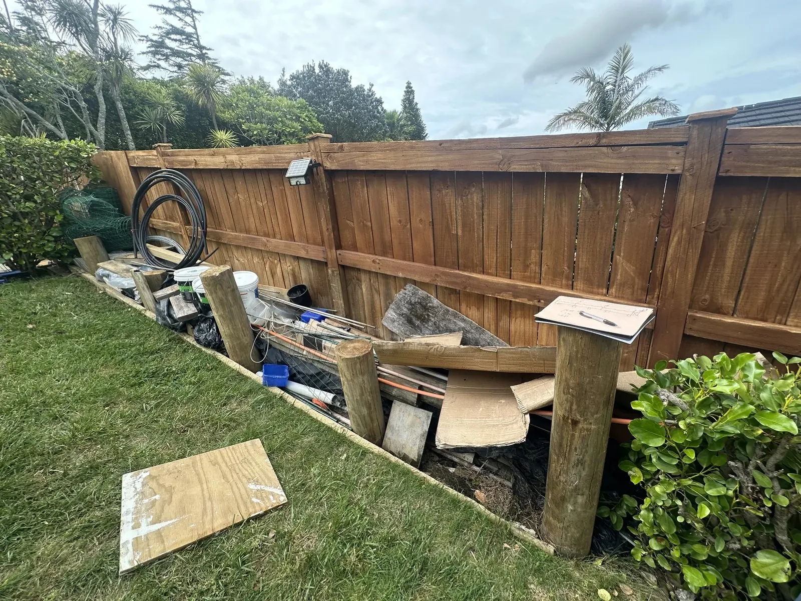 Unused sloping garden boundary area before custom storage construction in Dannemora