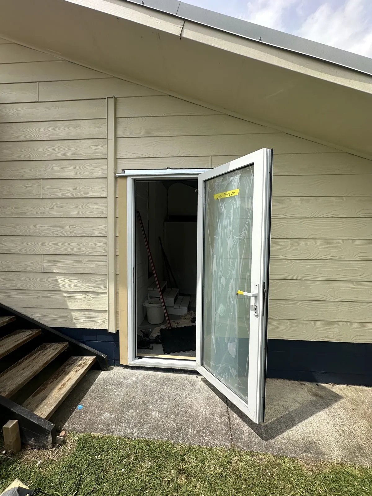 New aluminium door hung in the opening, protective film still on the glass, Half Moon Bay