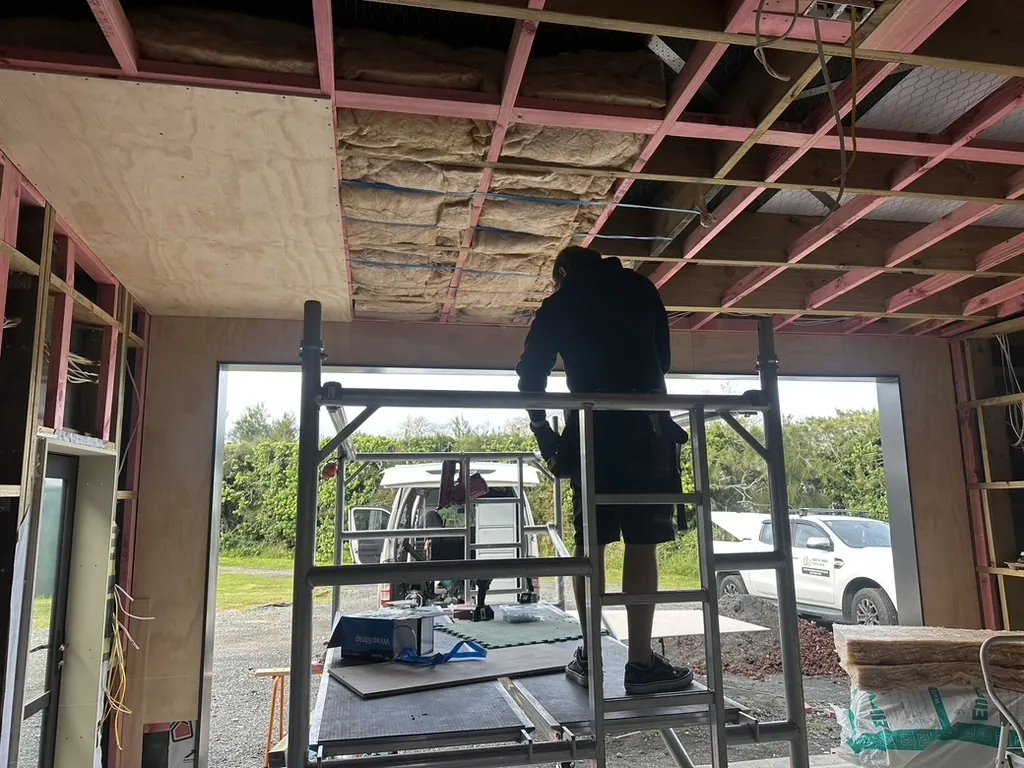 Plywood lining installation in progress from mobile scaffold during a three-day garage interior project in Whenuapai