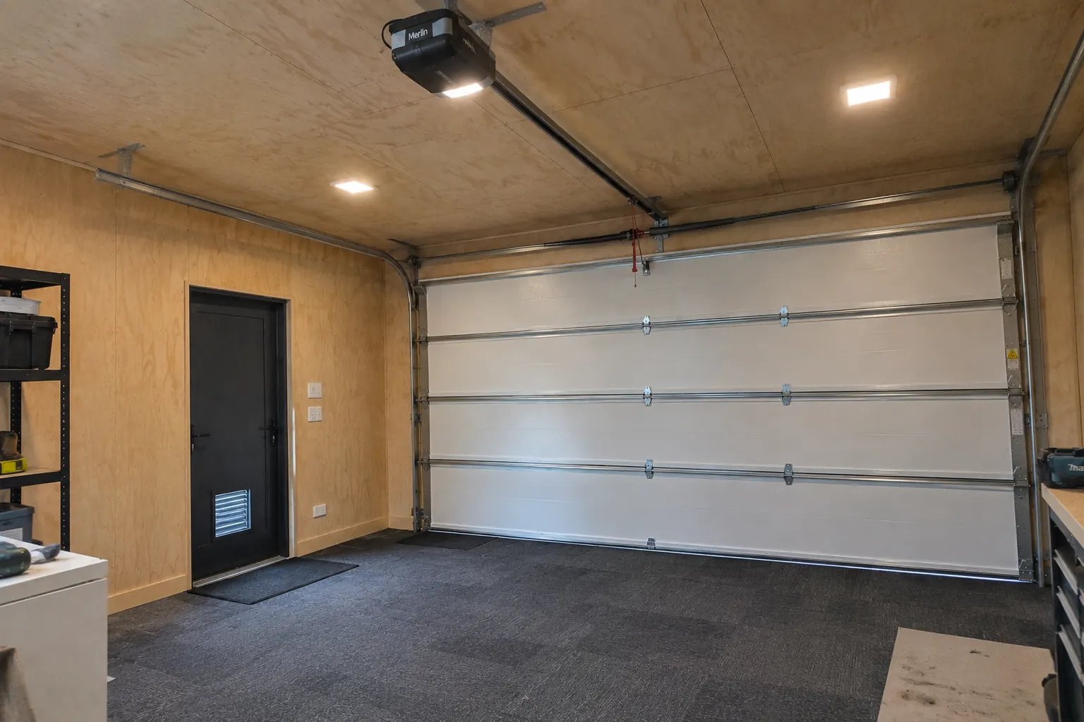 Finished garage interior after later completion by other trades, following framing, insulation and plywood lining works in Whenuapai
