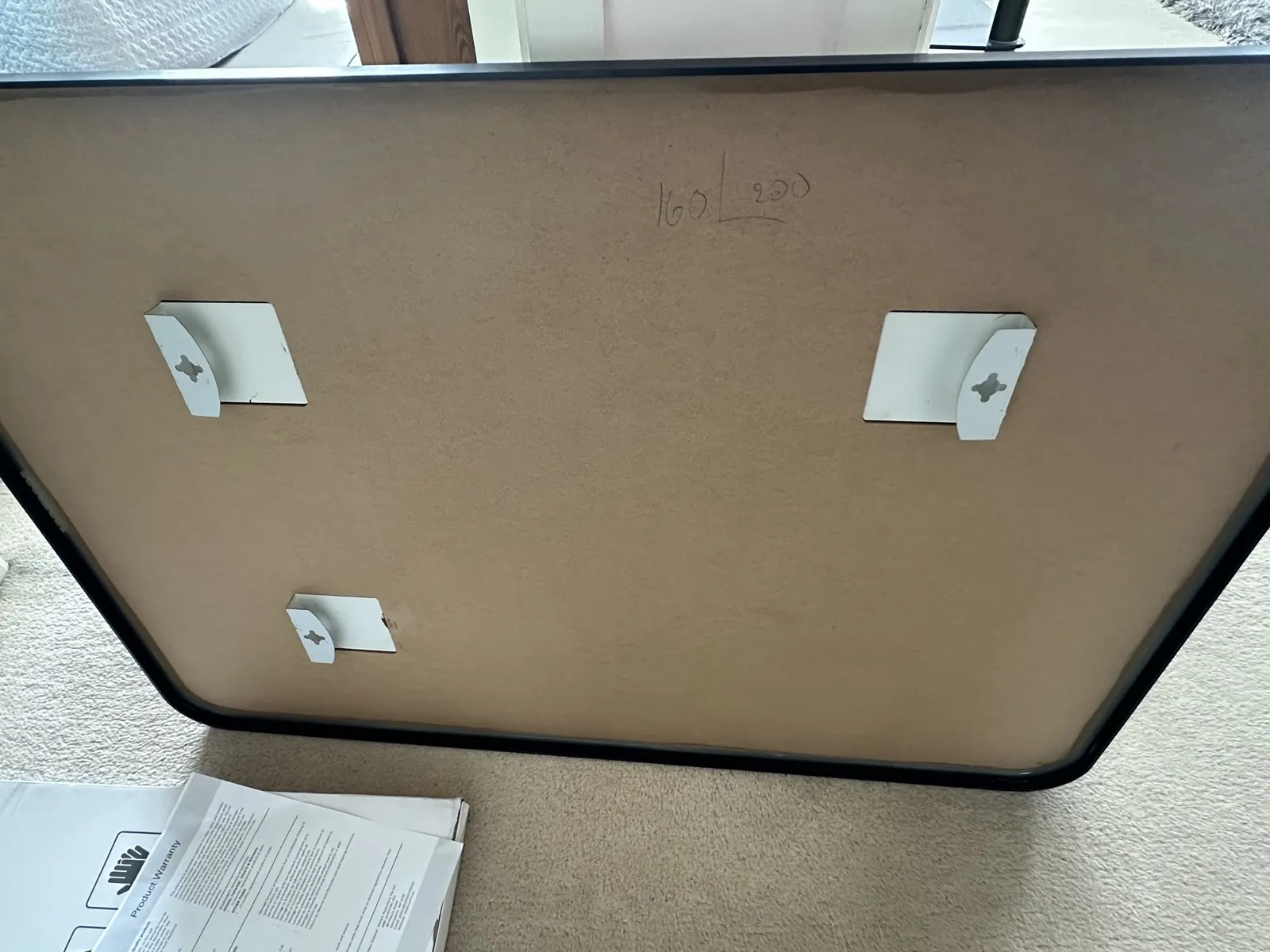 Back of the new framed mirror showing its keyhole hanging brackets, with the spacings written on in pencil