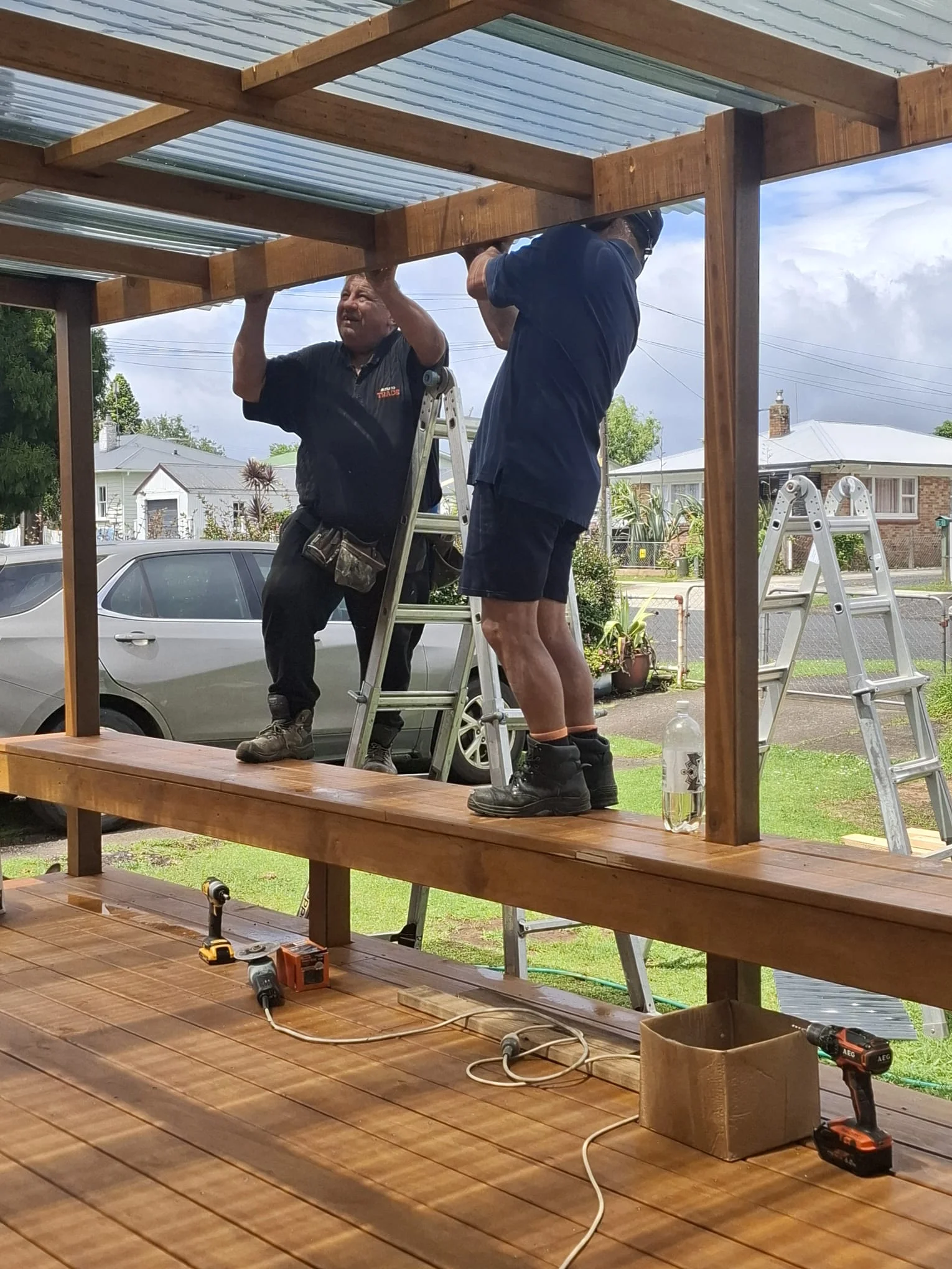 Two carpenters fitting the pergola roof framing on the new Tuakau deck