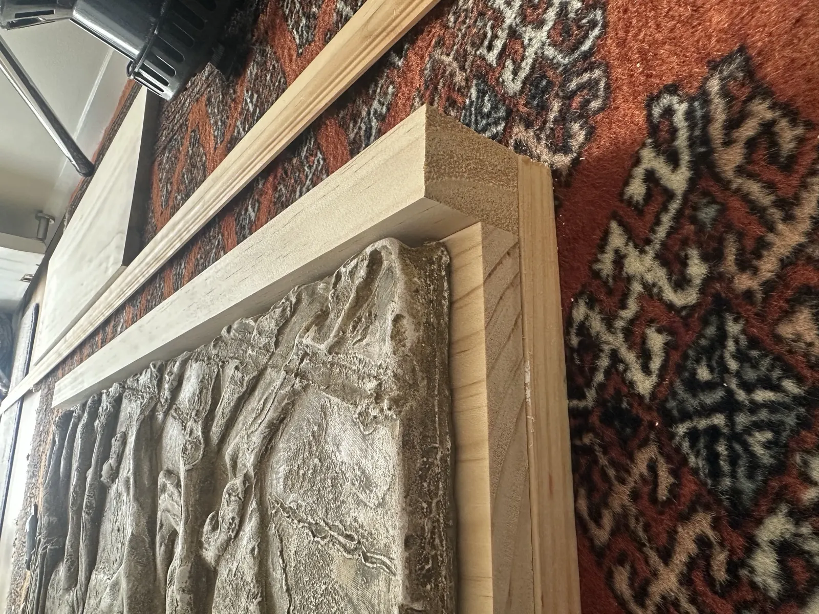Heavy cast relief panel with timber being offered up around its edge