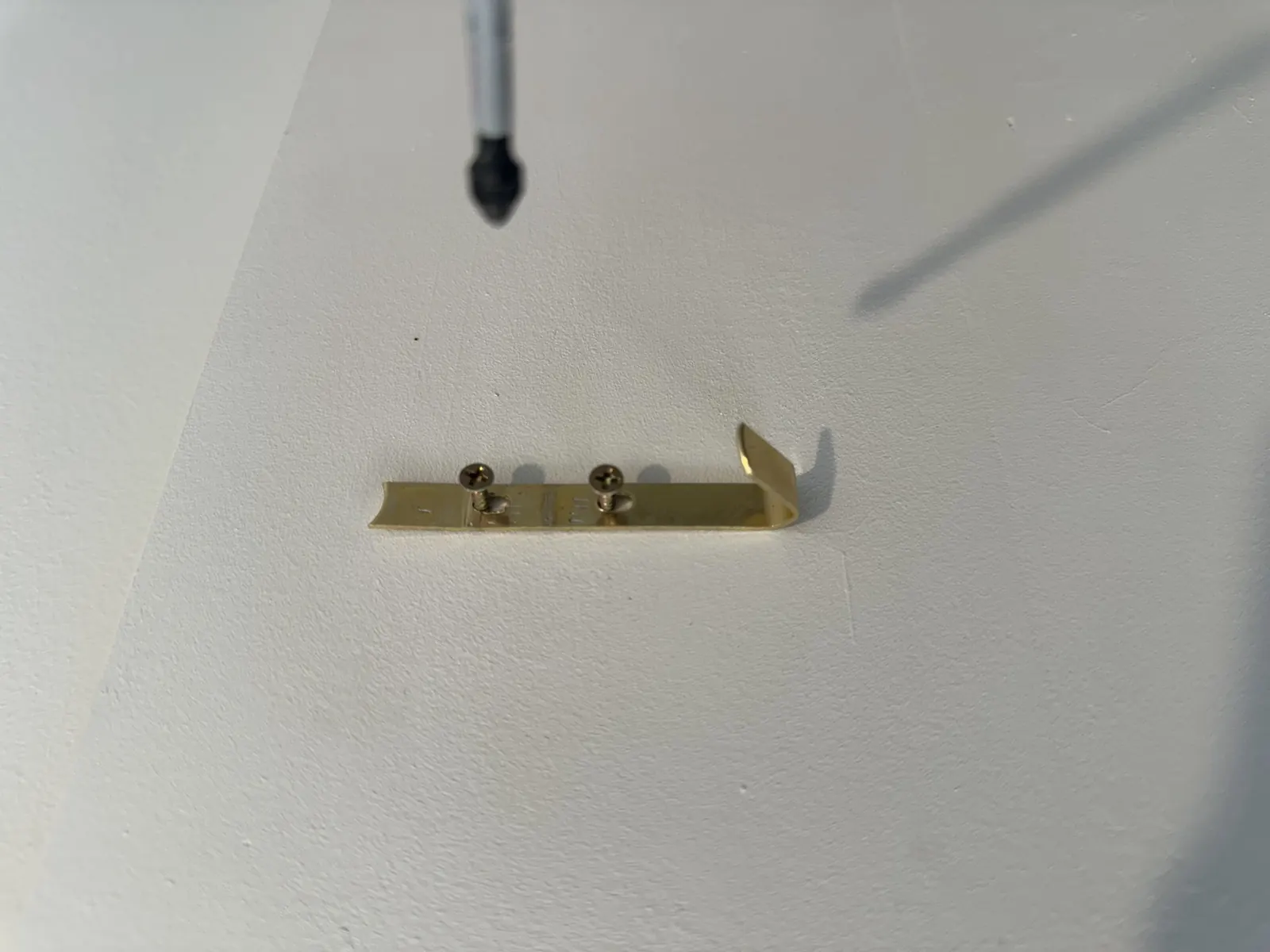 Brass picture hook screwed into an interior wall in Shelly Park