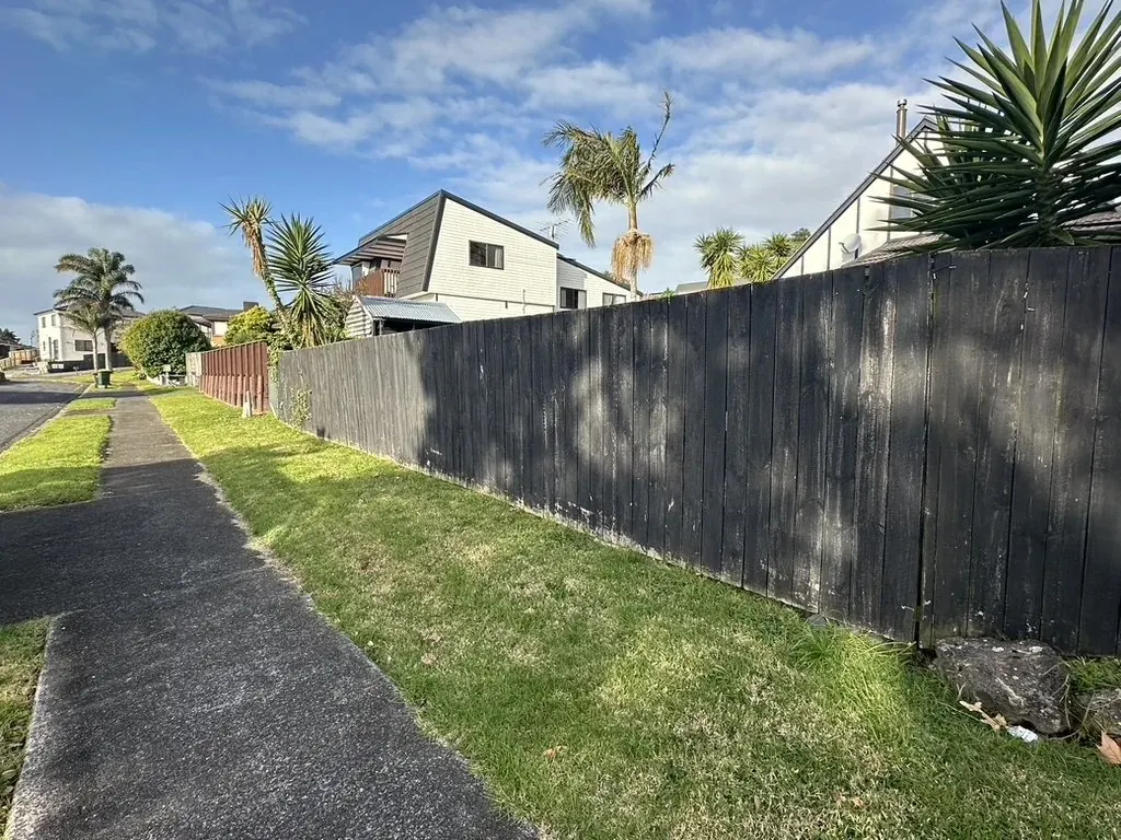 Long black timber fence cleaned by water blasting before repainting in Highland Park