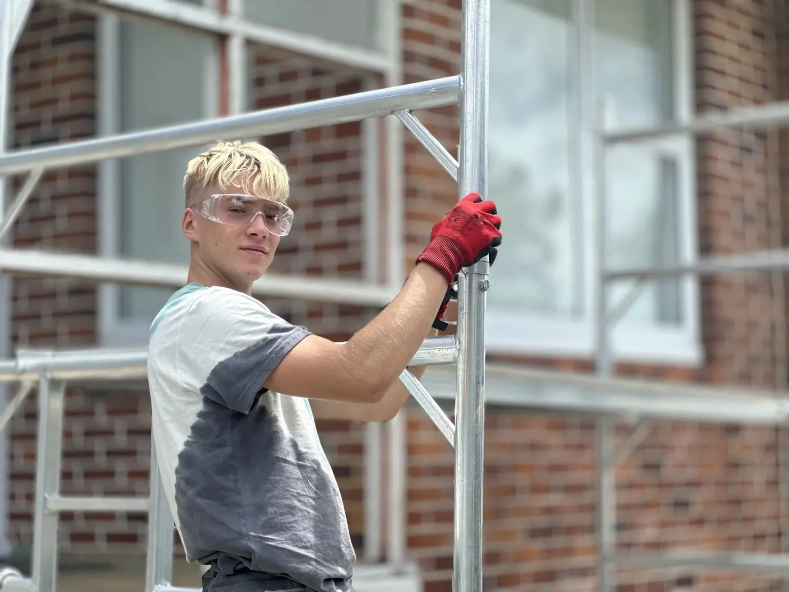 Apprentice Ravil wearing gloves and safety glasses beside scaffold in Howick