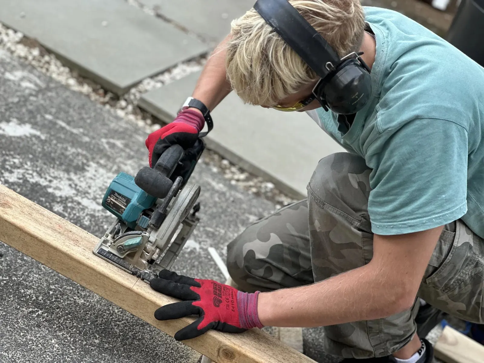 Apprentice cutting timber for an exterior wall while wearing eye and hearing protection