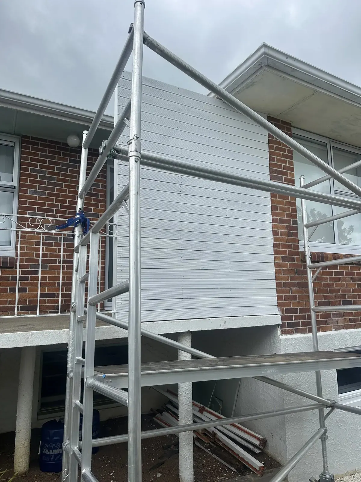 New horizontal exterior wall cladding near completion with scaffold access