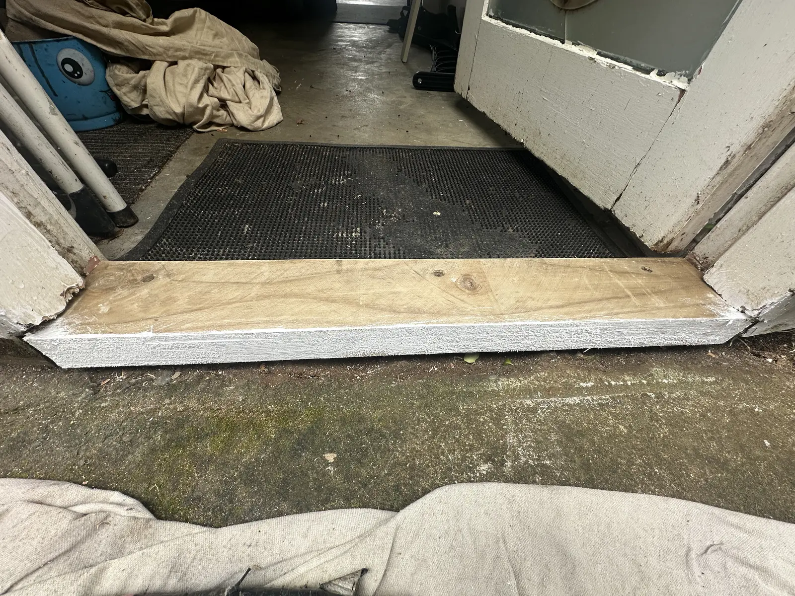 New timber threshold being fitted and painted at a garage entrance during rotten timber repair in East Tamaki, East Auckland