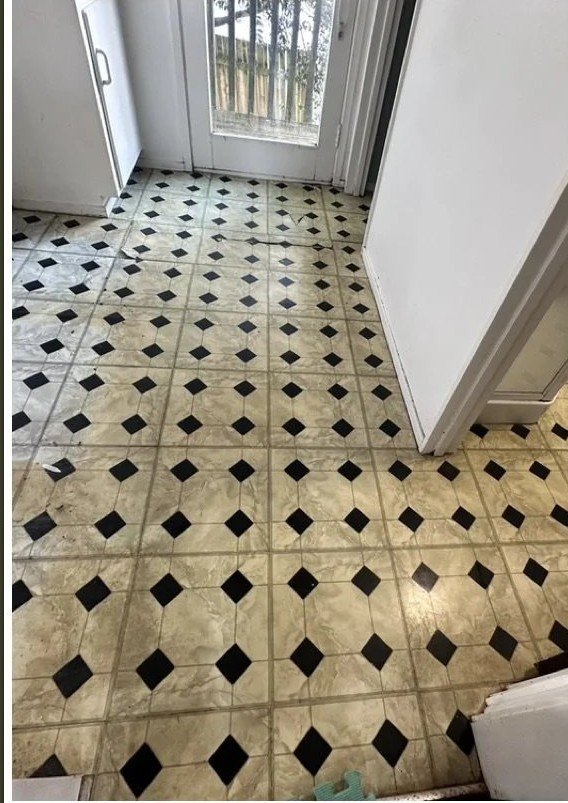 Old lifting, cracked square vinyl tiles in a Botany laundry corridor before replacement
