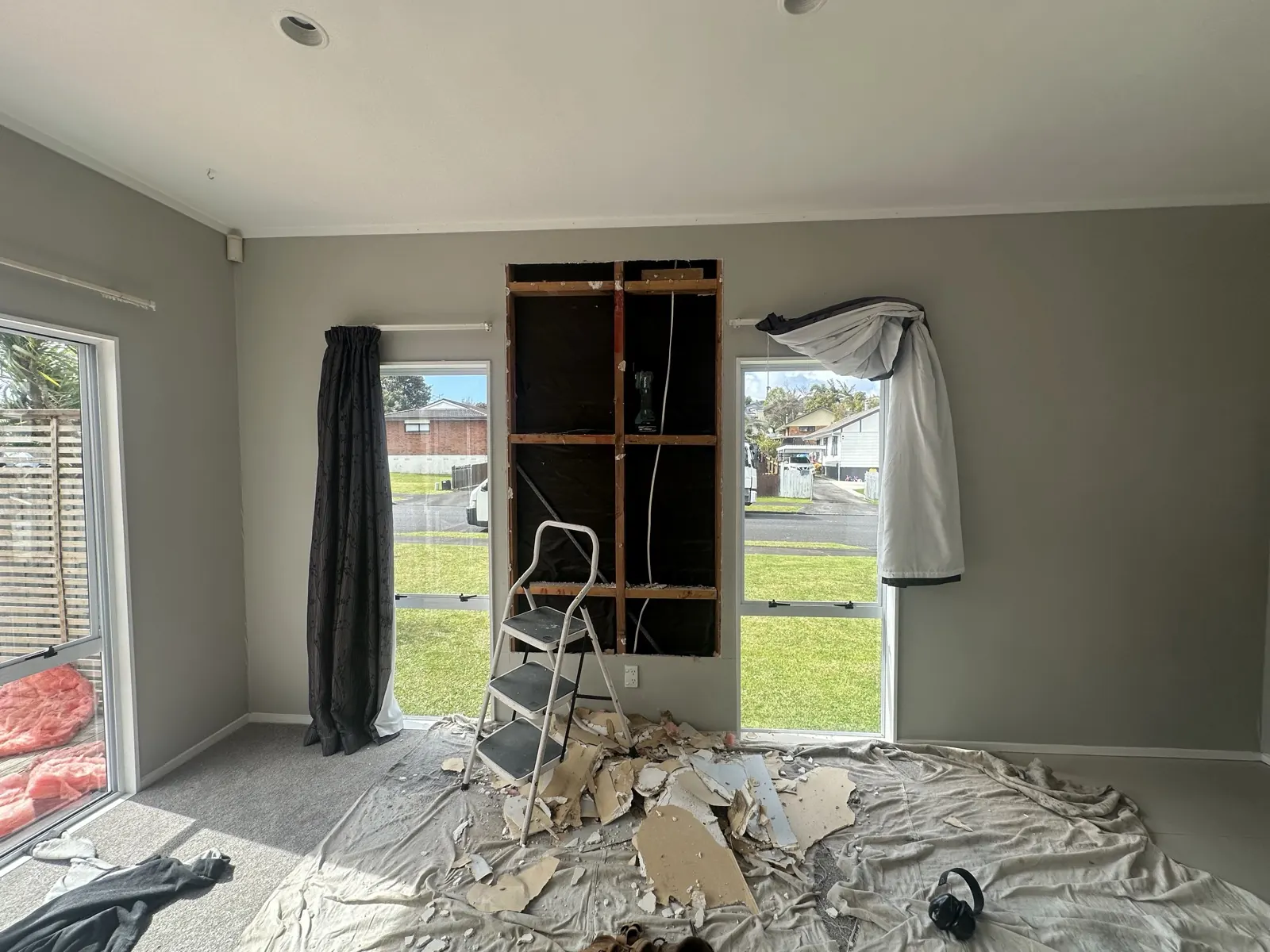 Wall lining opened up in a Highland Park living room after a leak was traced, exposing timber framing and black building paper