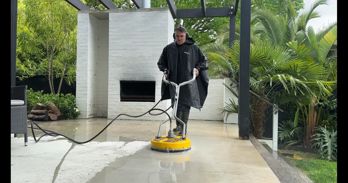 Rinat using a rotary concrete surface cleaner attachment on the BBQ area concrete in Pakuranga