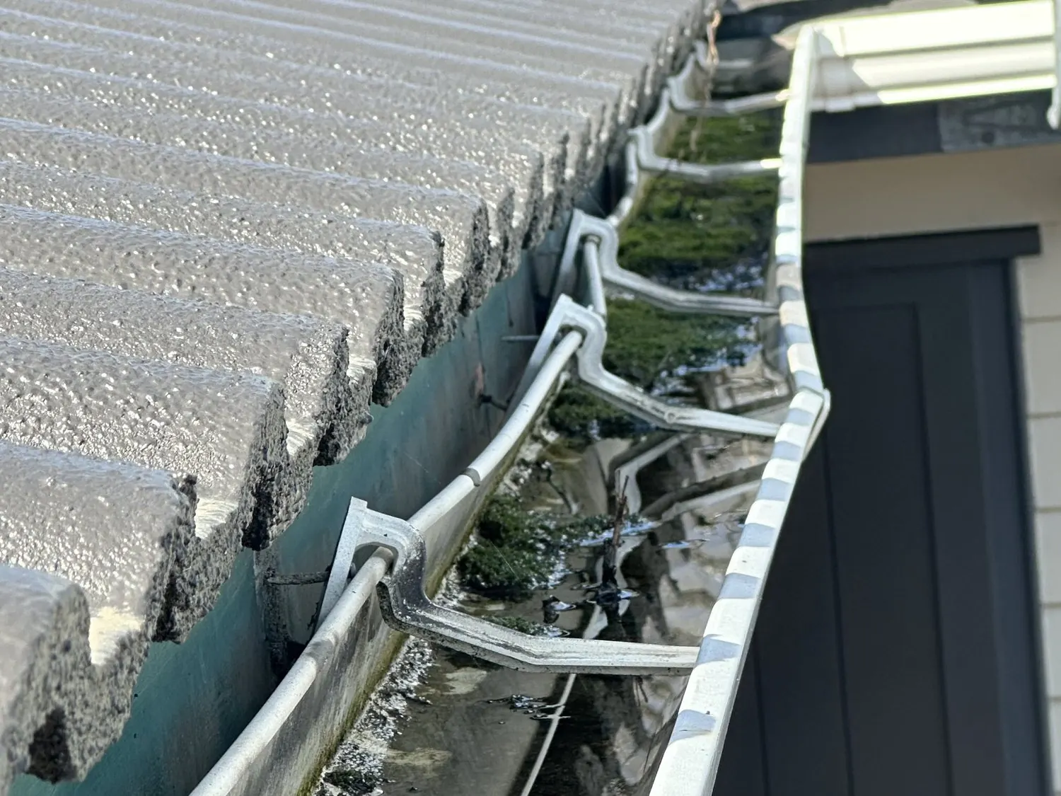 Gutter heavily blocked with wet roof debris before repair in Pakuranga Heights